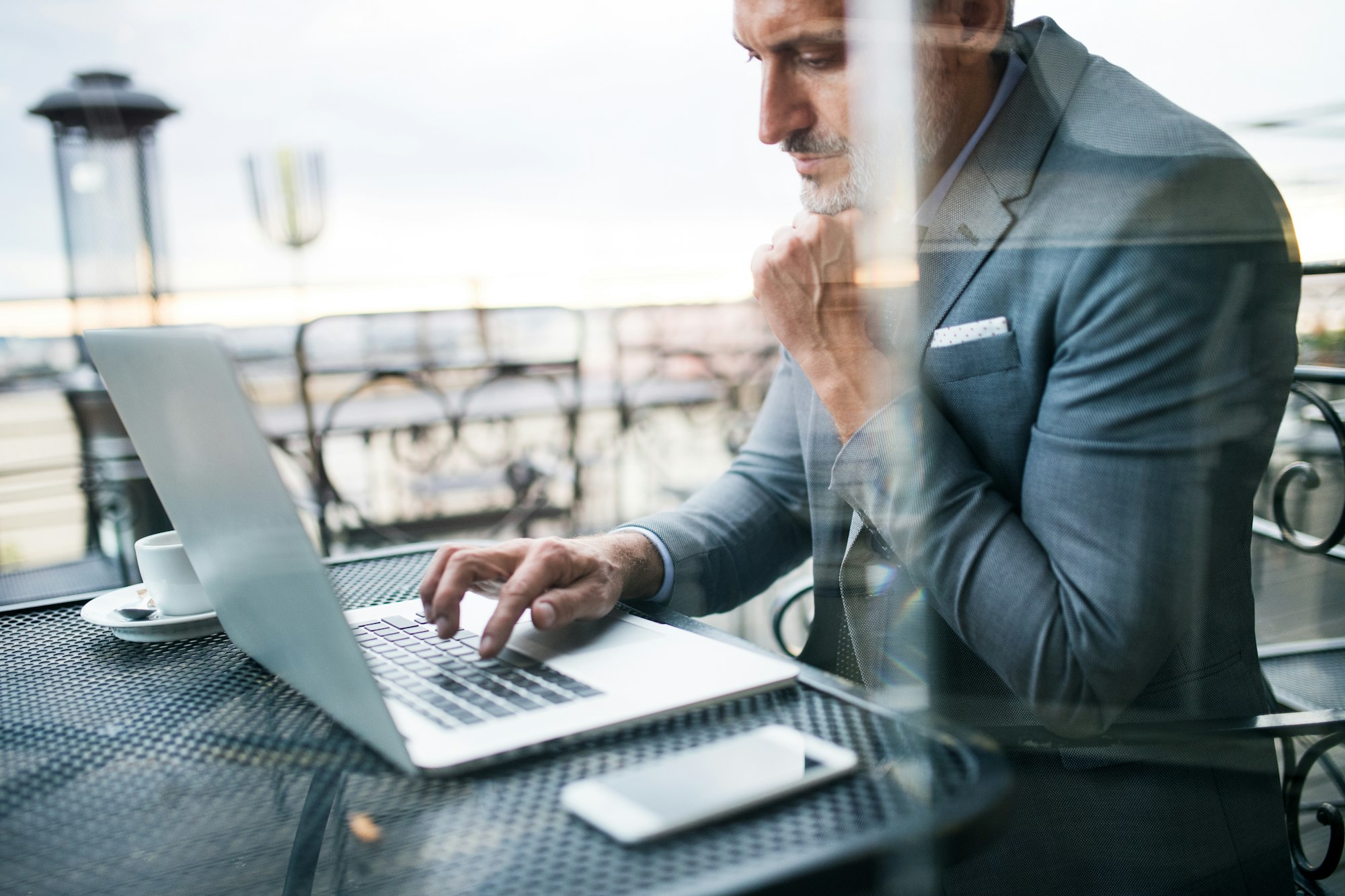 Mature businessman with laptop outside a cafe.